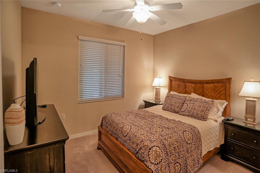 9727 Acqua Court, Unit 425 Naples, FL 34113 - Photo 13 of 26 a bedroom with a bed and a flat tv screen on a dresser