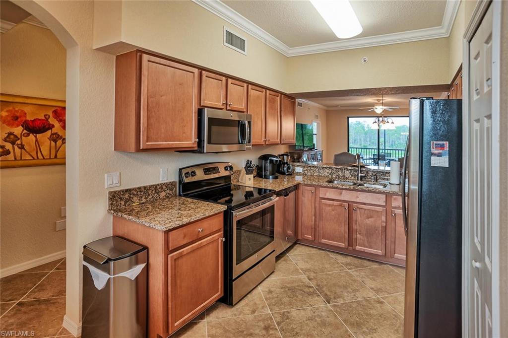 9727 Acqua Court, Unit 425 Naples, FL 34113 - Photo 7 of 26 a kitchen with stainless steel appliances granite countertop a stove sink and microwave