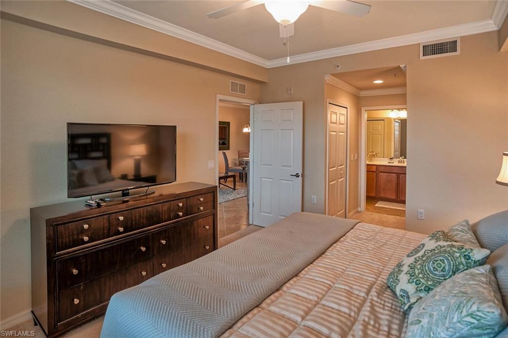 9727 Acqua Court, Unit 425 Naples, FL 34113 - Photo 10 of 26 a bedroom with a bed and a flat screen tv