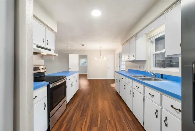 a large kitchen with stainless steel appliances granite countertop a lot of counter space and wooden floors