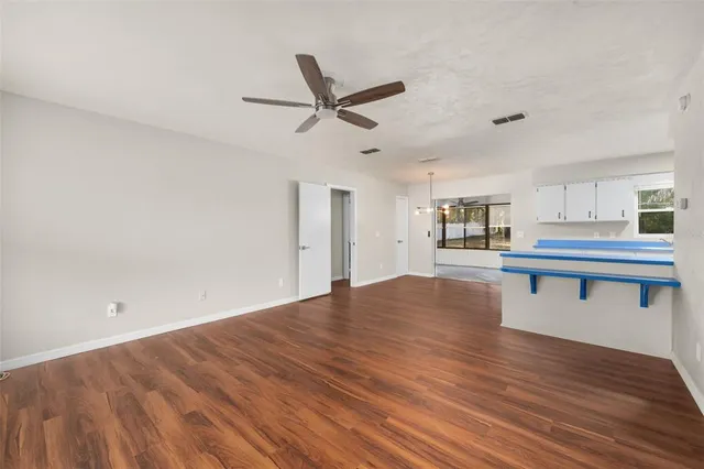 a view of kitchen and empty room with wooden floor