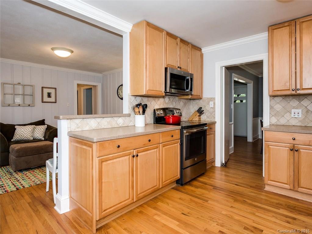 935 Scaleybark Road Charlotte, NC 28209 - Photo 6 of 17 a kitchen with stainless steel appliances granite countertop a stove top oven a sink dishwasher and white cabinets with wooden floor