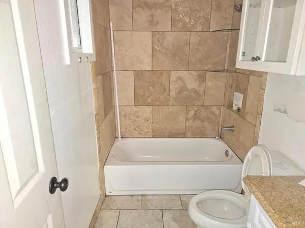 a bathroom with a granite countertop bathtub toilet and sink