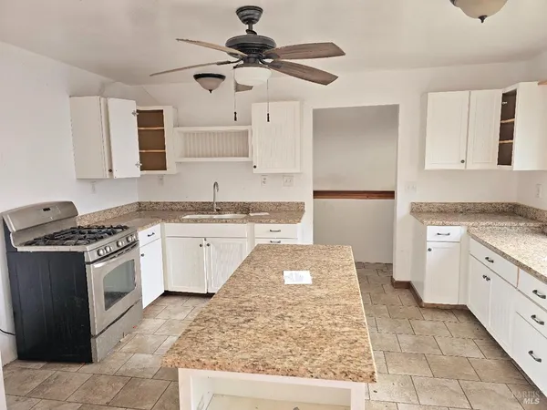 a kitchen with granite countertop a sink stove and refrigerator