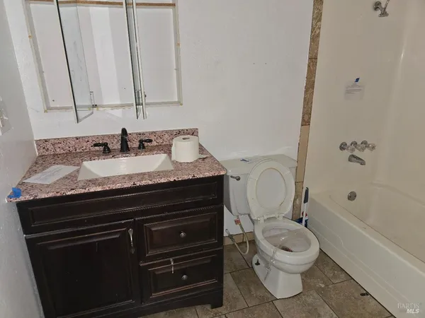 a bathroom with a granite countertop toilet sink and mirror
