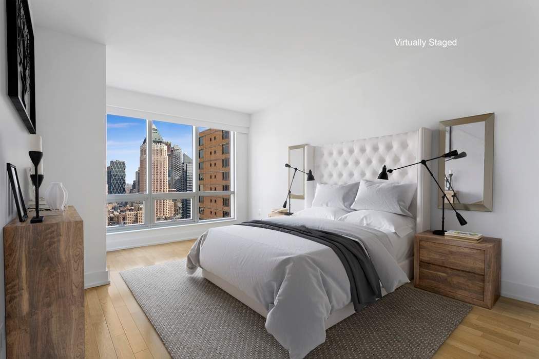 350 West 42nd Street, Unit 36B Manhattan, NY 10036 - Photo 6 of 17 a bedroom with a balcony a bed and a couch