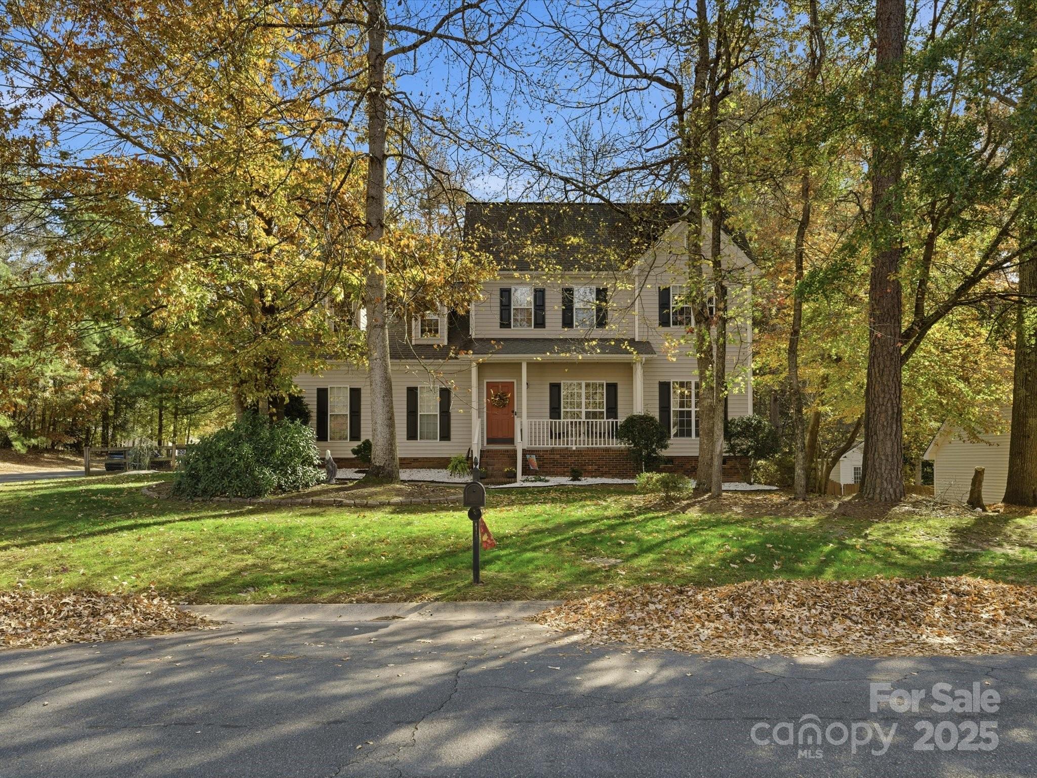 a view of a big house with a big yard and large trees