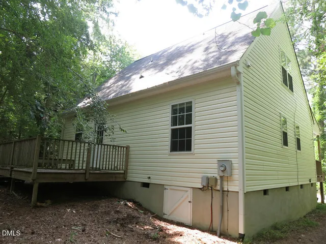 a view of a house with a wooden deck and a forest