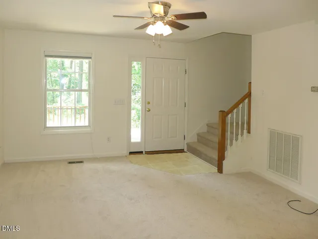 an empty room with chandelier fan and windows