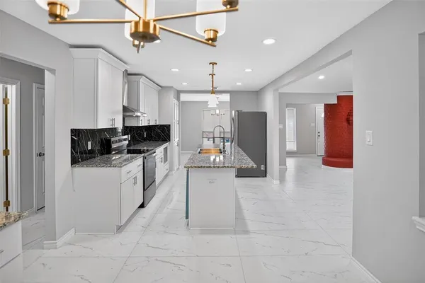 a kitchen with stainless steel appliances granite countertop a sink a stove a refrigerator a kitchen island with wooden cabinets and floor