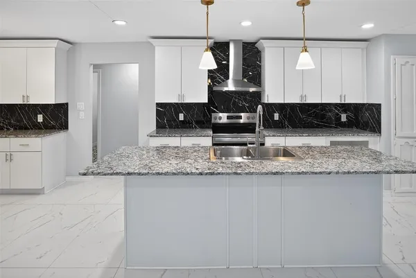 a kitchen with stainless steel appliances granite countertop a sink a stove a refrigerator white cabinets and wooden floor