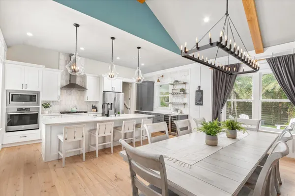 a kitchen with stainless steel appliances kitchen island granite countertop a table chairs in it and wooden floor