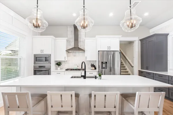 a kitchen with stainless steel appliances a dining table chairs refrigerator and cabinets