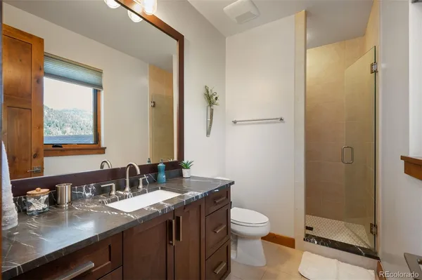 a bathroom with a granite countertop sink toilet and shower
