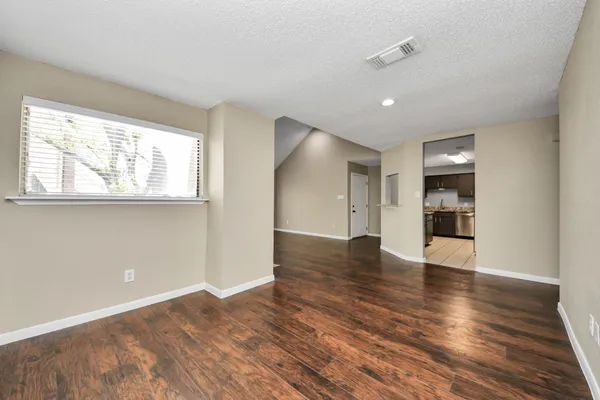 a view of an empty room with wooden floor and a window