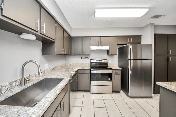 a kitchen with stainless steel appliances granite countertop a sink stove and refrigerator