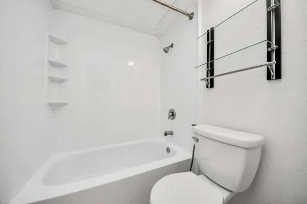 a white toilet sitting next to a bath tub