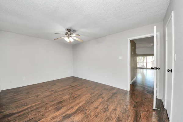 a view of a room with wooden floor and a ceiling fan