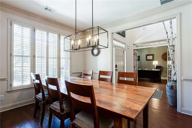 a dining room with wooden floor a chandelier a wooden table and chairs