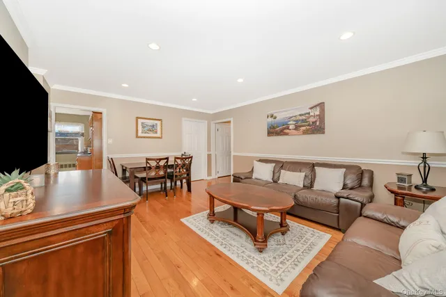 a living room with furniture and a flat screen tv with kitchen view