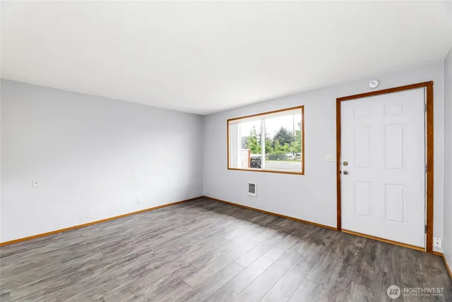 an empty room with wooden floor and window