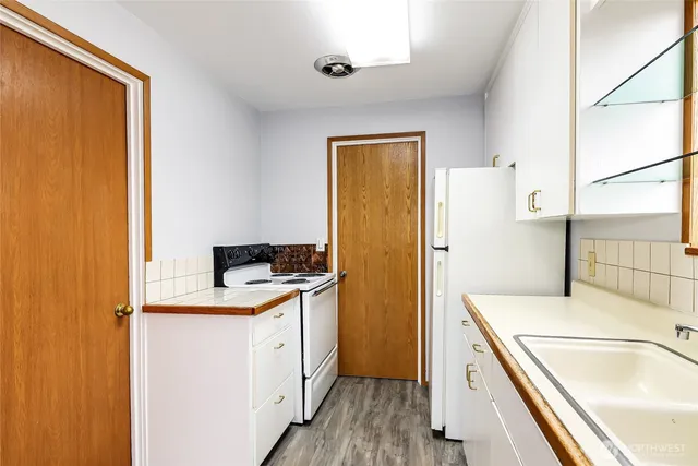 a kitchen with a refrigerator sink stove and wooden floor