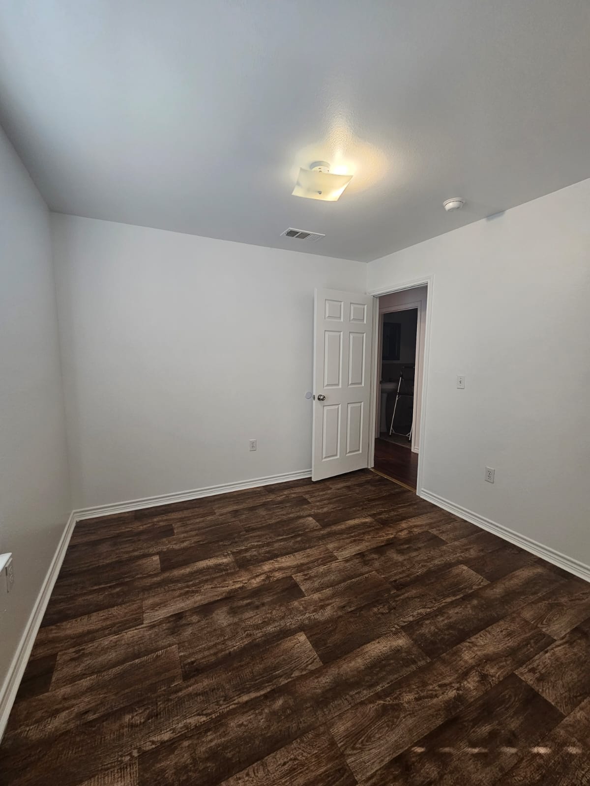 606 Trinity Street Lockhart, TX 78644 - Photo 10 of 23 Rich hardwood-style flooring extends across this bright, empty room, ready for your personal touch.