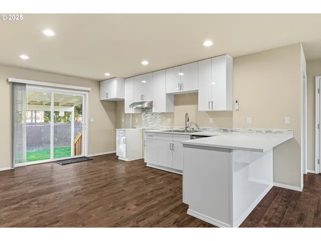a open kitchen with white cabinets and wooden floor