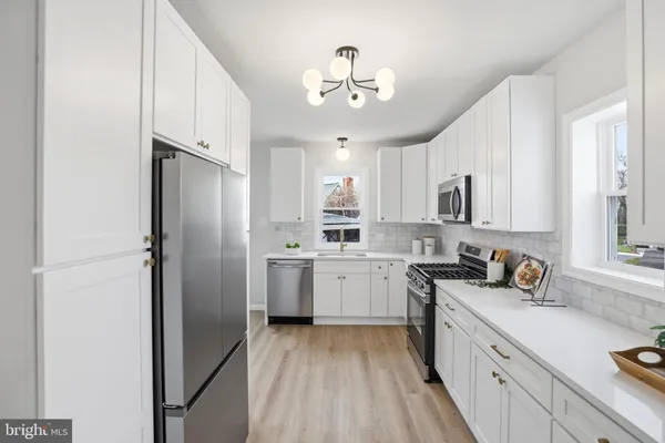 a kitchen with a sink stainless steel appliances cabinets and a window