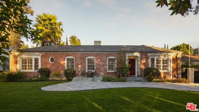 a front view of a house with a yard and potted plants