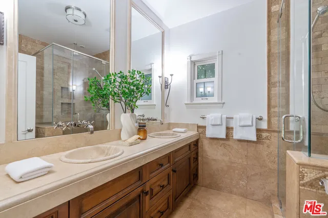 a bathroom with a granite countertop sink a large mirror and a shower