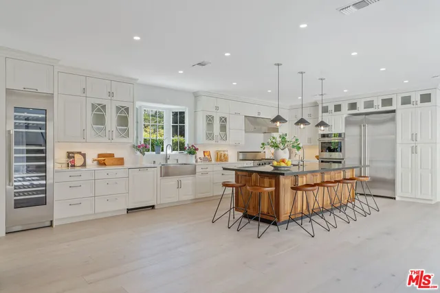 a large white kitchen with kitchen island a large counter space and stainless steel appliances