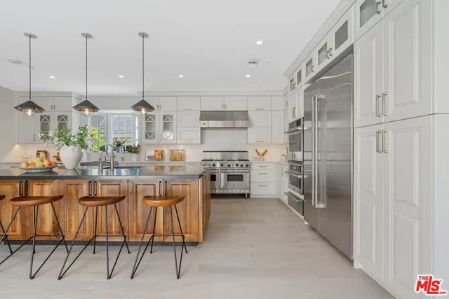 a kitchen with stainless steel appliances kitchen island granite countertop a table chairs sink and cabinets