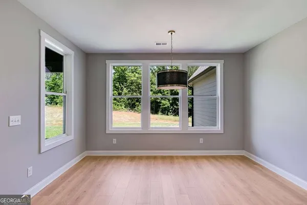 a view of an empty room with a window and wooden floor