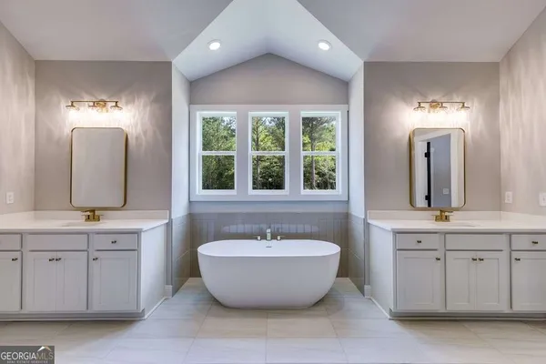 a spacious bathroom with a double vanity sink a two mirror a window and a bathtub