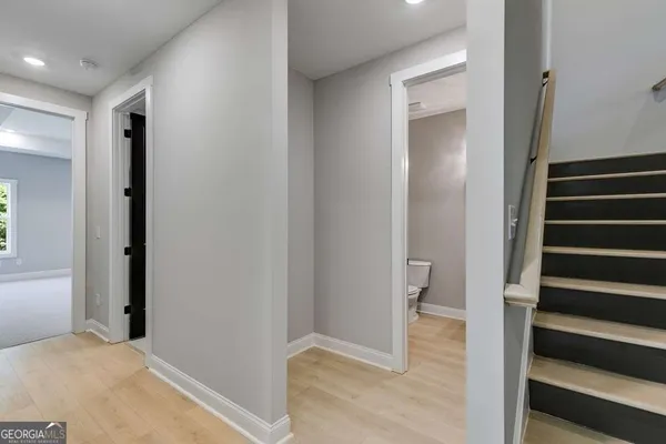 a view of a hallway with wooden floor and staircase