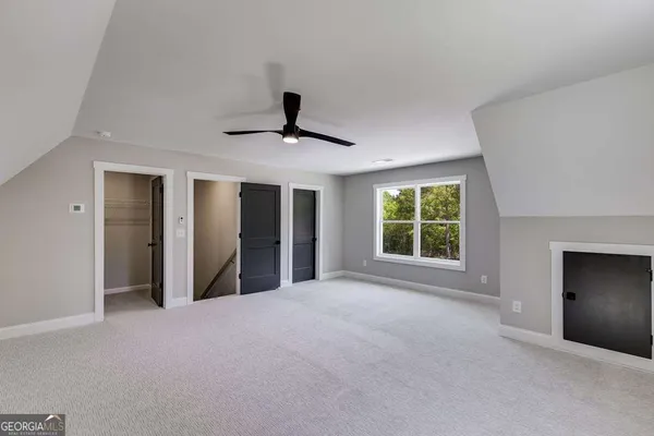 a view of an empty room with a window and a kitchen