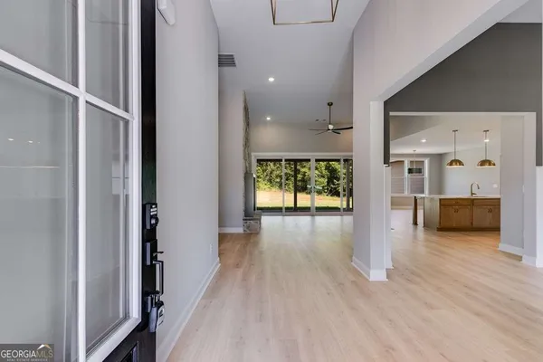 a view of a hallway view with wooden floor and a living room