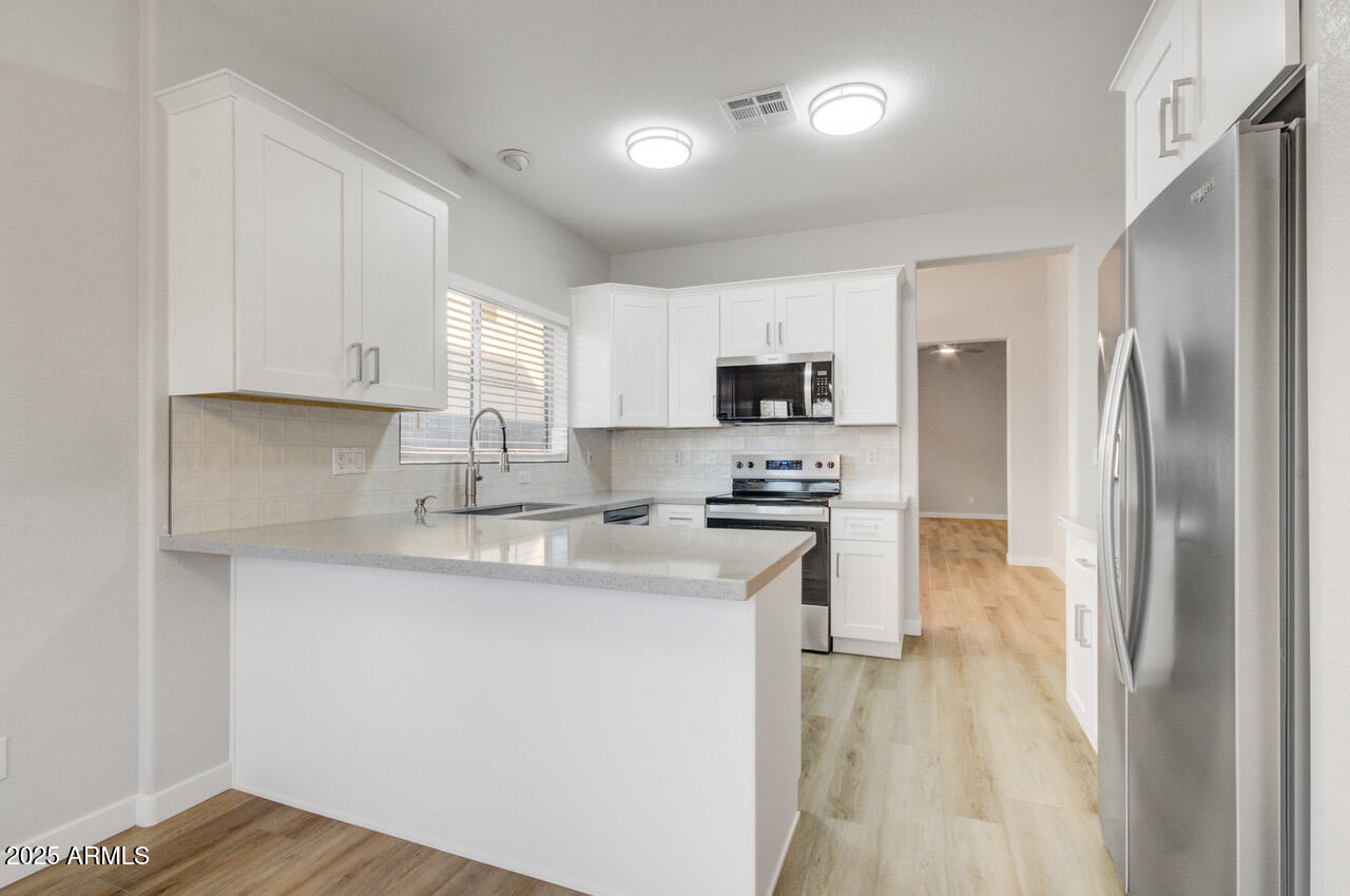 13431 West Evans Drive Surprise, AZ 85379 - Photo 4 of 37 a kitchen with kitchen island a sink stainless steel appliances and white cabinets