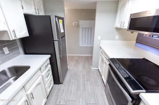 a kitchen with stainless steel appliances a refrigerator a sink a stove and white cabinets