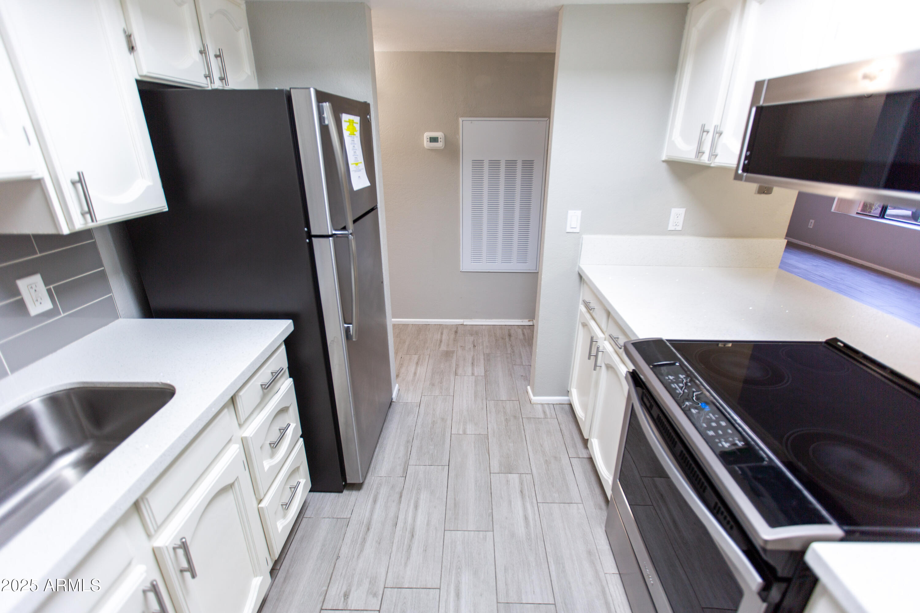 1402 East Guadalupe Road, Unit 153 Tempe, AZ 85283 - Photo 6 of 25 a kitchen with stainless steel appliances a refrigerator a sink a stove and white cabinets