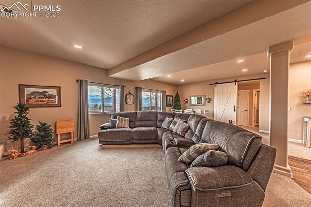 13812 Windy Oaks Road Colorado Springs, CO 80921 - Photo 45 of 50 Carpeted living room with a textured ceiling, visible vents, baseboards, recessed lighting, and a barn door