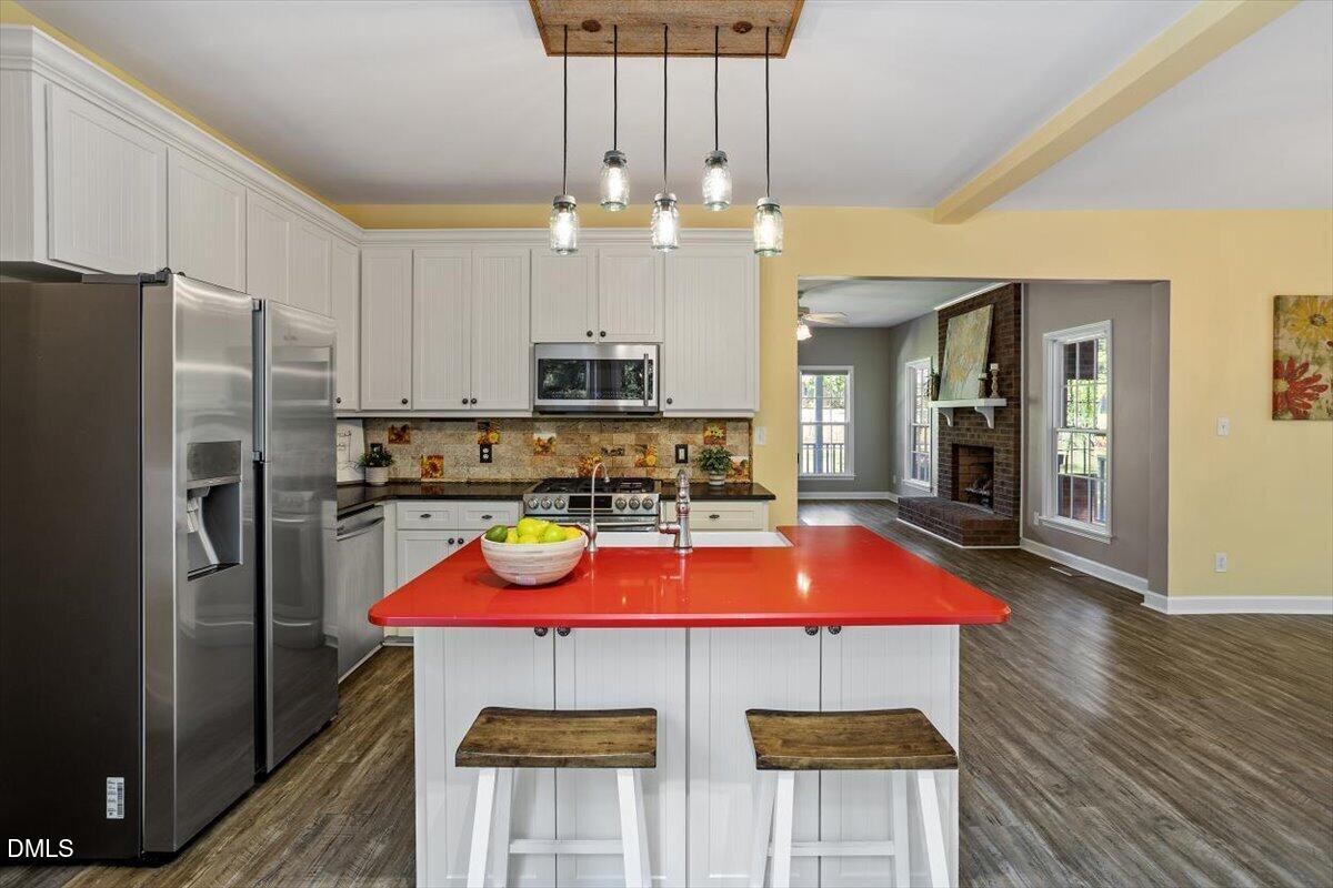 7505 Penny Road Raleigh, NC 27606 - Photo 18 of 35 a kitchen with stainless steel appliances a table chairs refrigerator and microwave