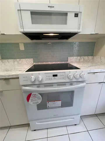 a kitchen with granite countertop white cabinets and white appliances