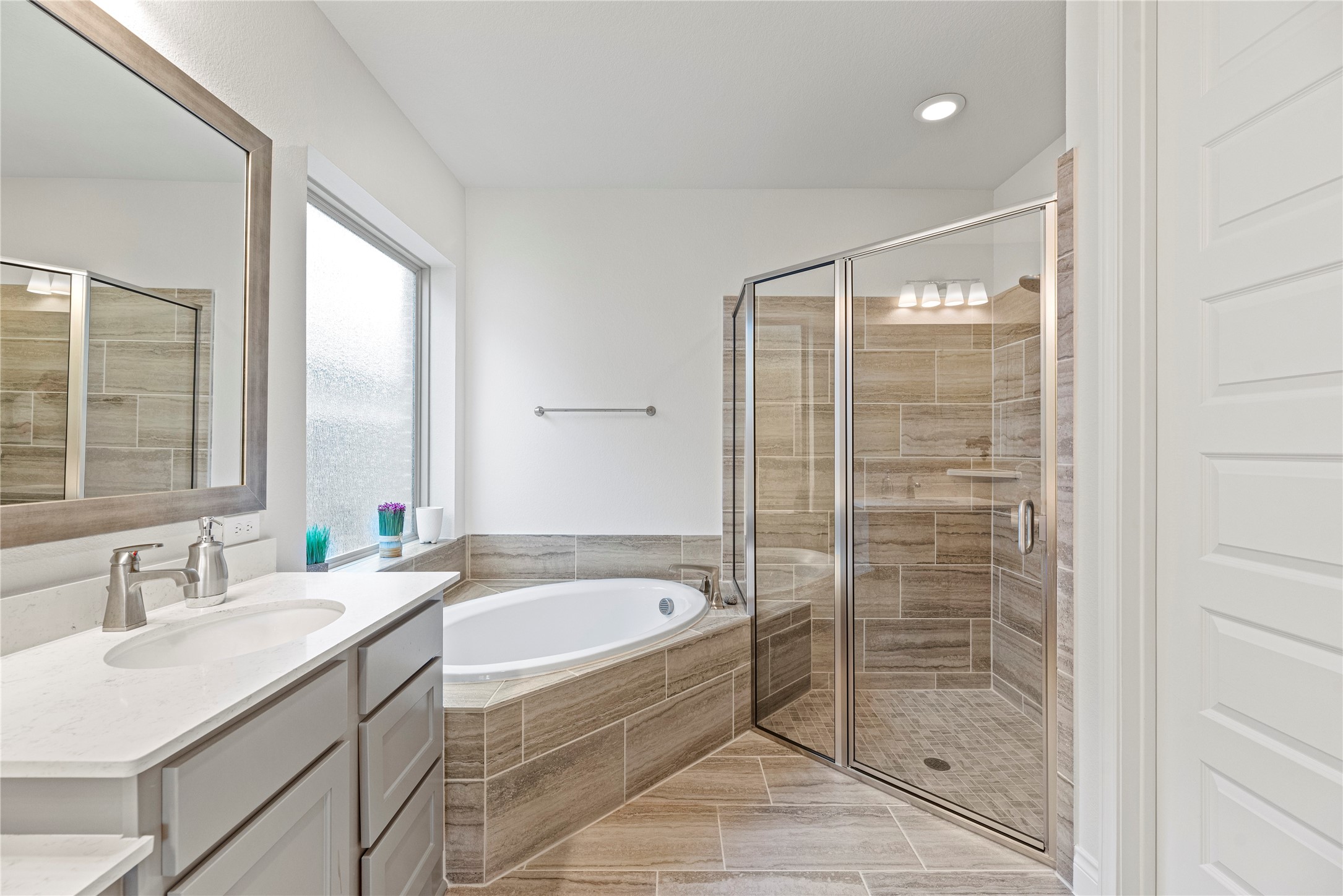 6938 Amberwing Way Katy, TX 77493 - Photo 16 of 38 a bathroom with a granite countertop sink a mirror a bathtub and next to a window