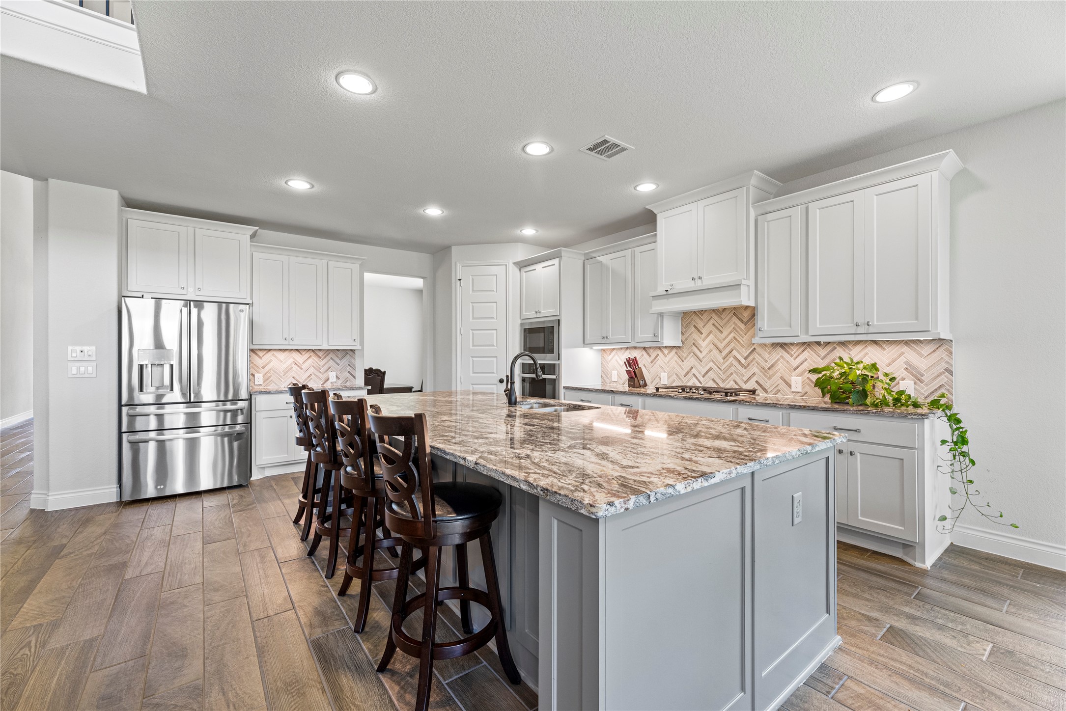 6938 Amberwing Way Katy, TX 77493 - Photo 2 of 38 a kitchen with stainless steel appliances granite countertop a table chairs sink refrigerator and cabinets