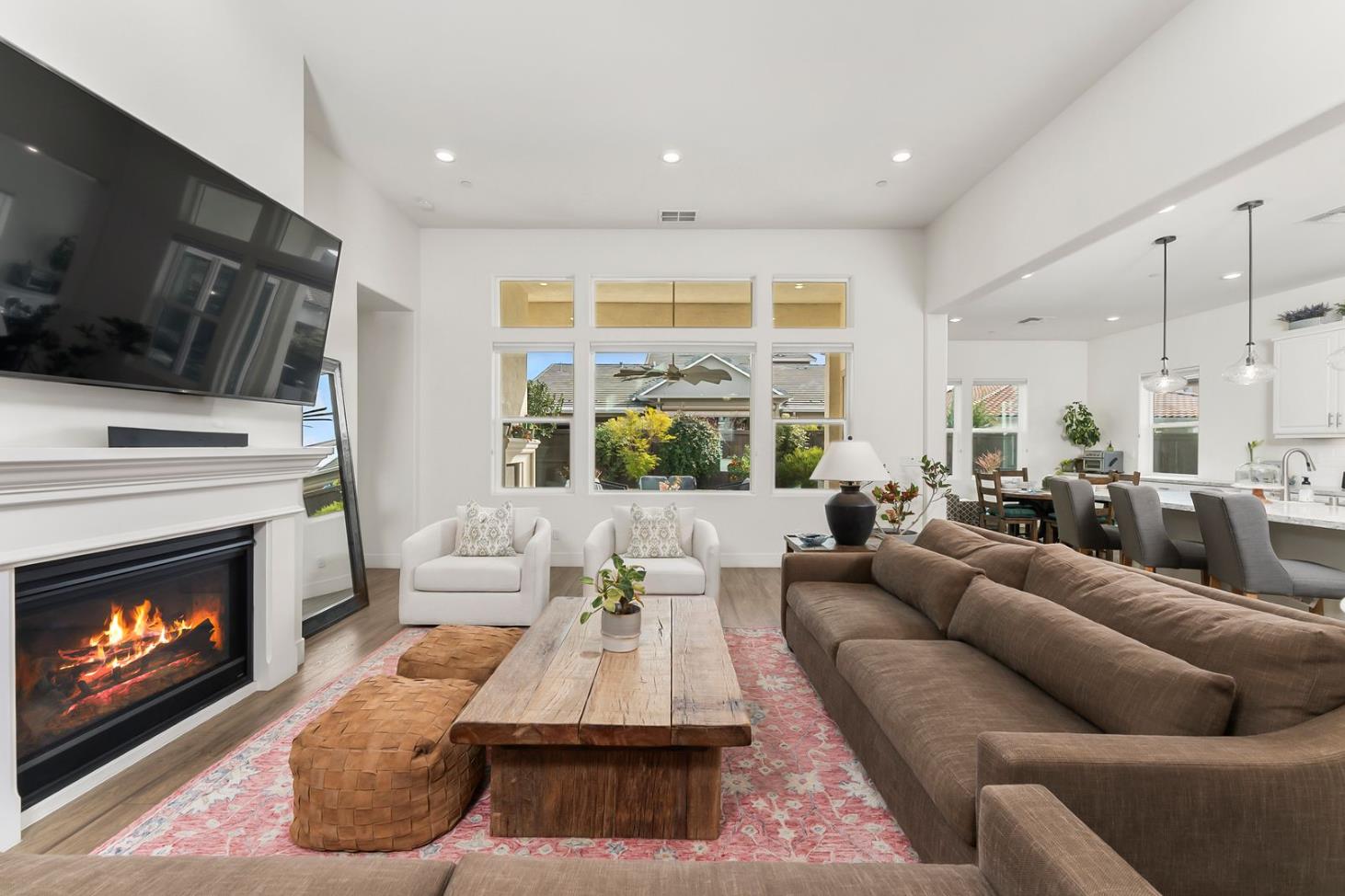 1509 Harvest Loop Folsom, CA 95630 - Photo 84 of 92 THE MAIN LOUNGE embodies soaring ceilings embraced by a series of transom windows, flooding the open communal floor plan with tons of natural light. This entire home is LIGHT, BRIGHT AND AIRY! Added to the exquisite design are the stunning, super durable water and scratch proof wide board luxury vinyl plank flooring. Despite its spacious square feet, the central lounge and dining room are still one of the most charming shared areas of the residence, featuring the cast concrete fireplace and mantel, triple transom windows, and adjacent double door den/study/office/salon flex space....breath taking!