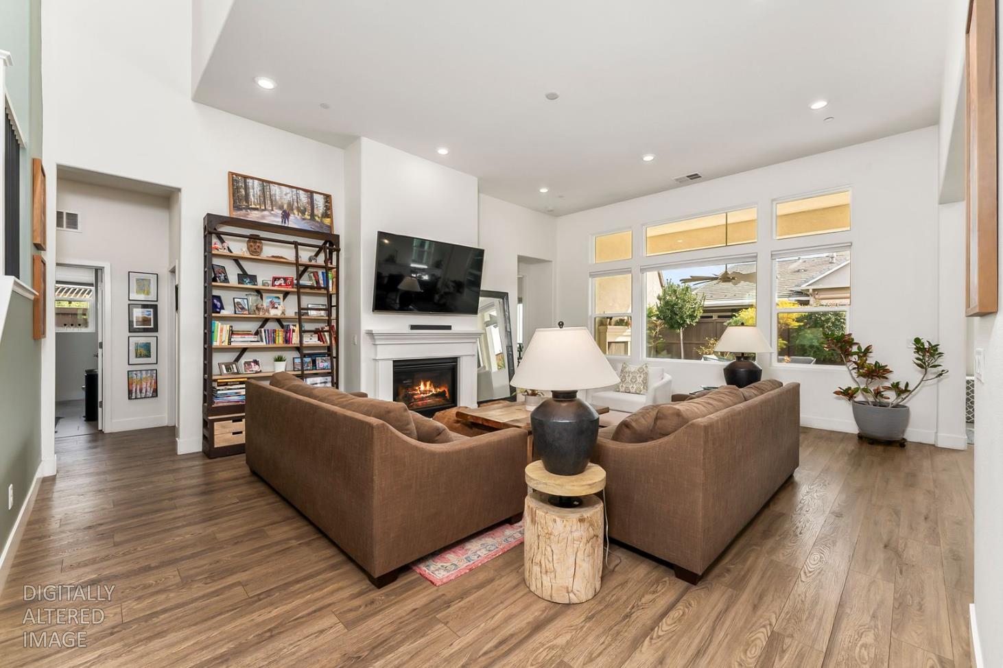 1509 Harvest Loop Folsom, CA 95630 - Photo 87 of 92 THE MAIN LOUNGE embodies soaring ceilings embraced by a series of transom windows, flooding the open communal floor plan with tons of natural light. This entire home is LIGHT, BRIGHT AND AIRY! Added to the exquisite design are the stunning, super durable water and scratch proof wide board luxury vinyl plank flooring. Despite its spacious square feet, the central lounge and dining room are still one of the most charming shared areas of the residence, featuring the cast concrete fireplace and mantel, triple transom windows, and adjacent double door den/study/office/salon flex space....breath taking!
