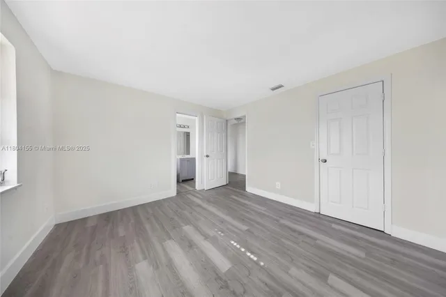 a view of an empty room with wooden floor and closet