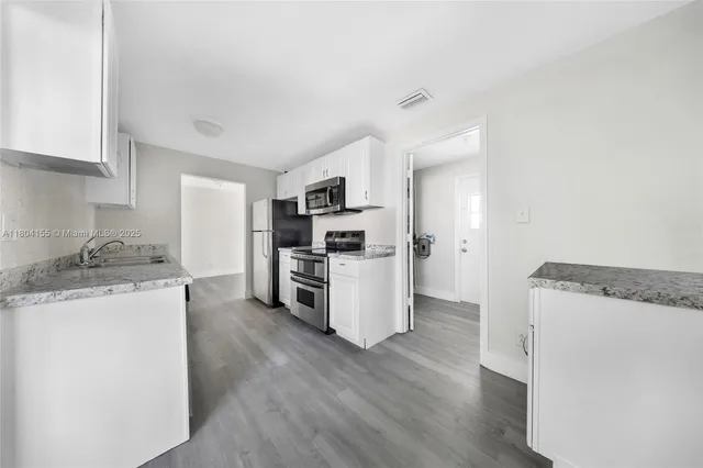 a kitchen with granite countertop a refrigerator and a stove top oven